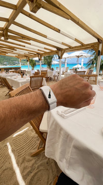 Bracelet QUIETUDE DonPé blanc porté au poignet à la table d'un restaurant