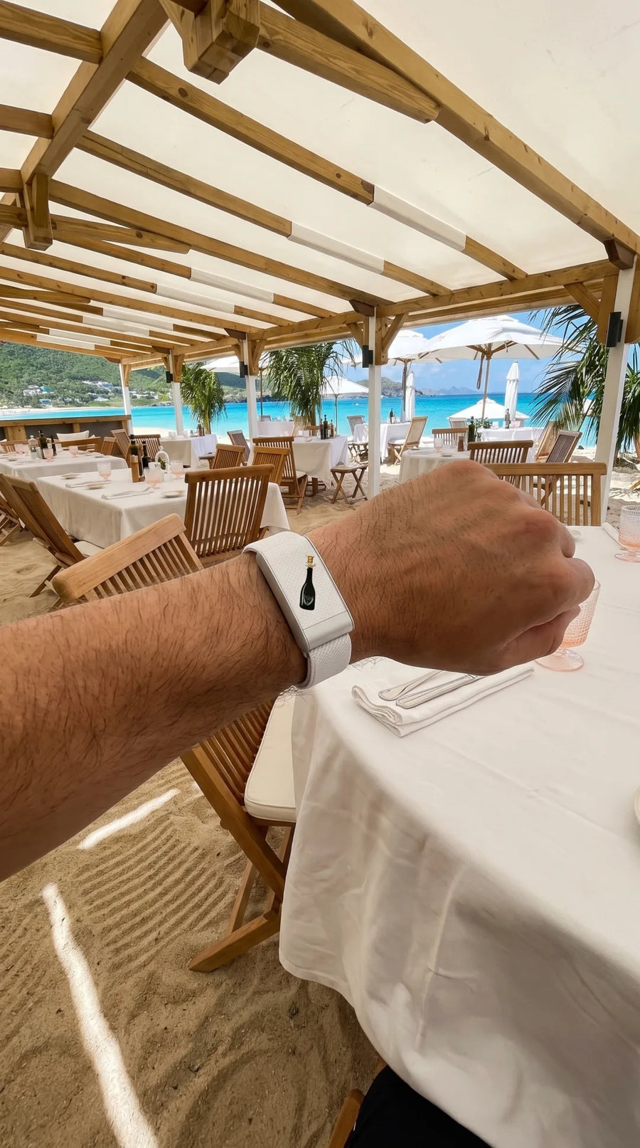 Bracelet QUIETUDE DonPé blanc porté au poignet à la table d'un restaurant